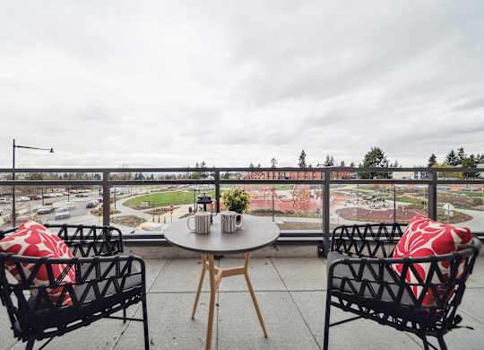 Two chairs and a table with a view of a street and trees.