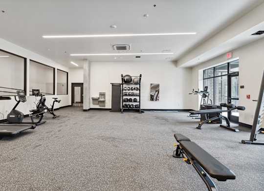 A spacious gym with a variety of equipment including treadmills, exercise bikes, and weight racks.