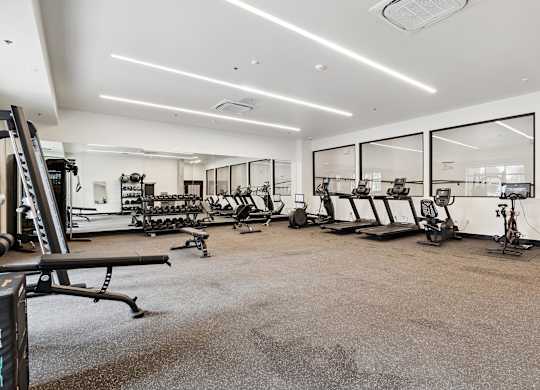 A spacious gym with a variety of equipment including treadmills, exercise bikes, and weight machines.