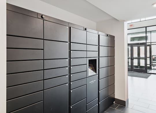 A black metal locker with a mail slot is in a hallway.
