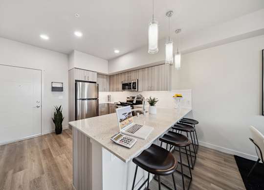 A kitchen with a bar area and a laptop on the counter.