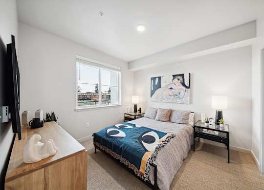 A bedroom with a bed, nightstand, and a television.