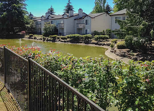 A beautiful garden with a pond and a fence.