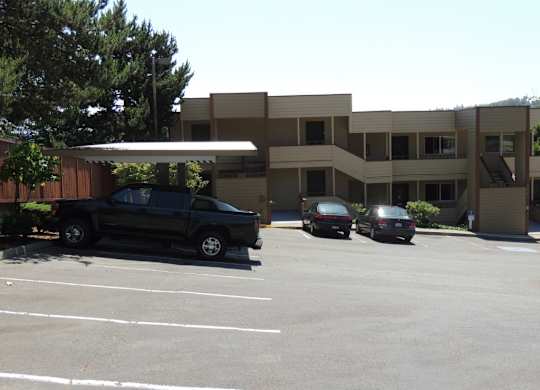 A black truck is parked in a parking lot in front of a building.
