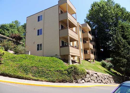 A beige apartment building with a green lawn in front.