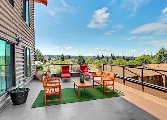 A balcony with a table and chairs overlooking a green landscape.