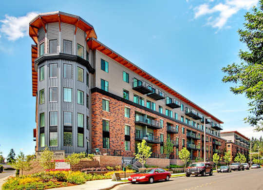 A modern multi-story building with a red car parked in front.