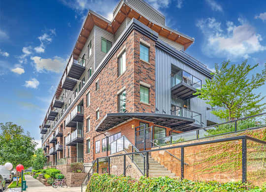 A modern apartment building with a red brick facade and balconies.