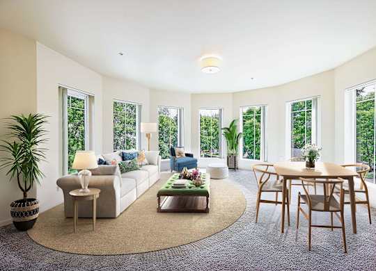 A living room with a white couch, a coffee table, and a large window.