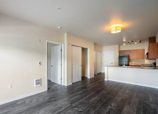 A spacious room with a kitchen area in the background.