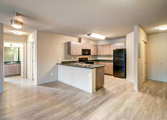 A kitchen with a black fridge and a wooden island.