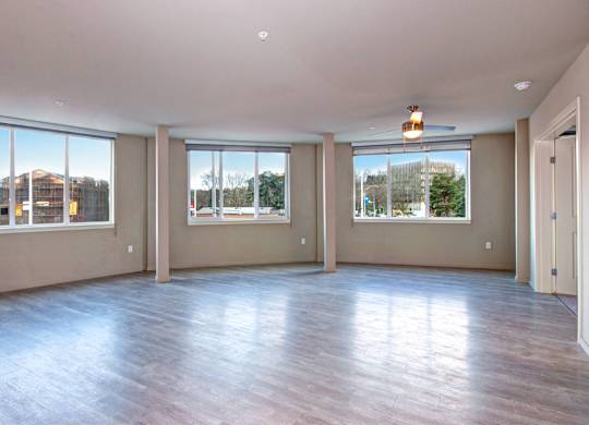 A large empty room with wooden floors and windows.