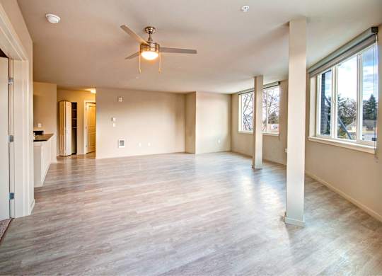 A spacious room with a ceiling fan and wooden flooring.