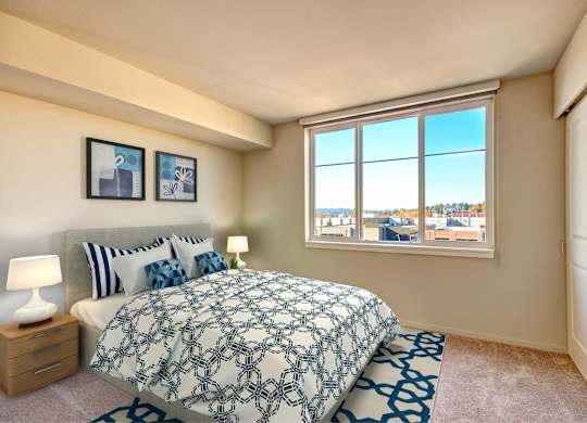 A bedroom with a large bed and a window overlooking a cityscape.