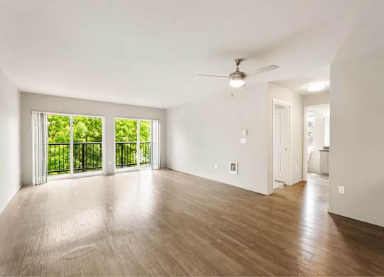 A room with a ceiling fan and sliding glass doors.