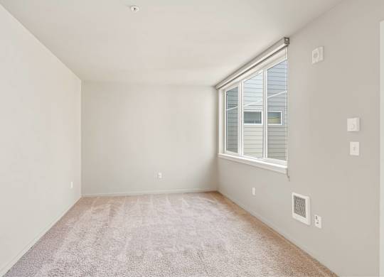 A room with a window and a carpet on the floor.