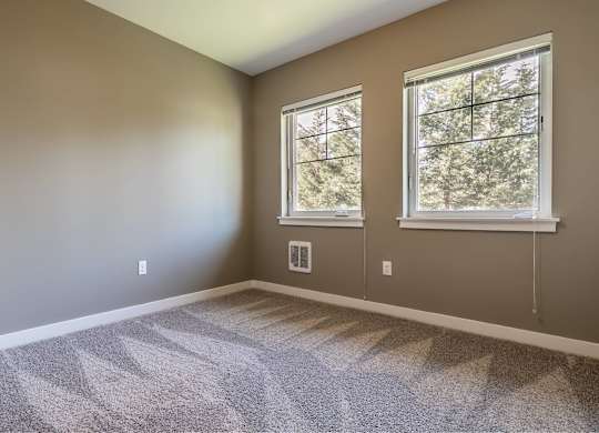 A room with two windows and carpeted floor.