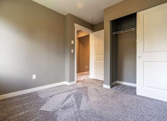 A room with a carpeted floor and a doorway leading to another room.