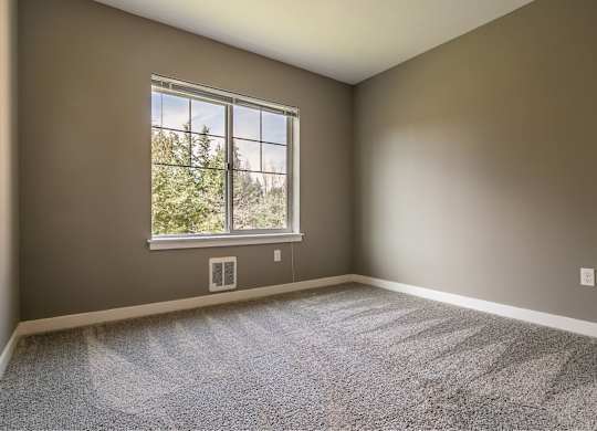 A room with a large window and carpeted floor.