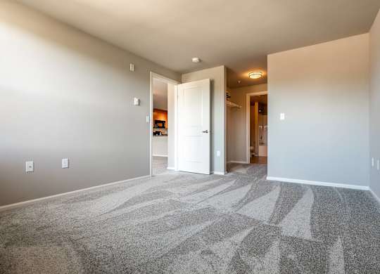 A hallway with a carpeted floor and white walls.