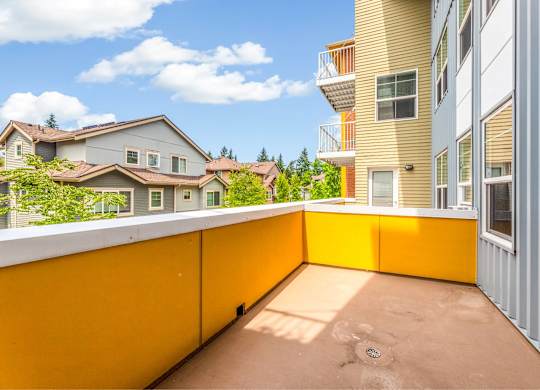A balcony with a yellow railing overlooks a residential area.