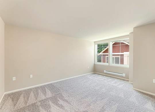 A room with a carpeted floor and a window showing a red building outside.