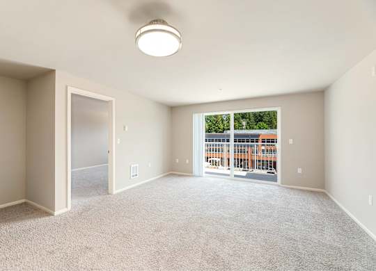 A spacious room with a carpeted floor and a window overlooking a construction site.