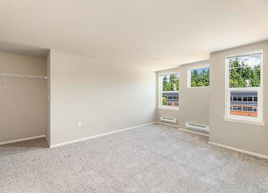 Empty room with carpeted floor and two windows.