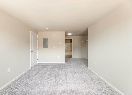 A spacious room with a carpeted floor and white walls.