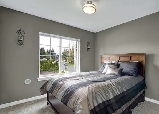 A bedroom with a bed, a window, and a painting on the wall.