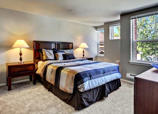 A bedroom with a large bed and two lamps.