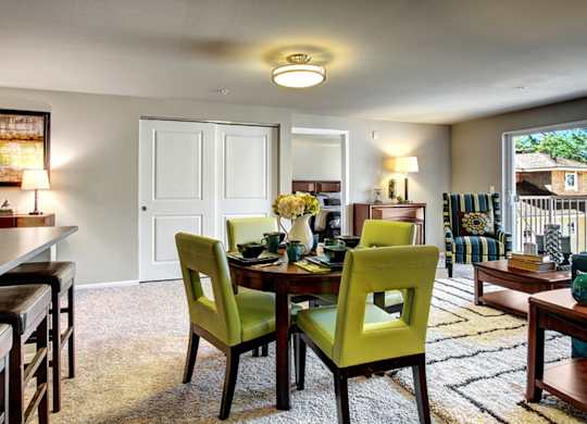 A dining room with a table set for two and green chairs.