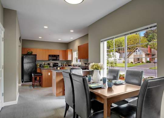 A kitchen with a table and chairs in front of a window.