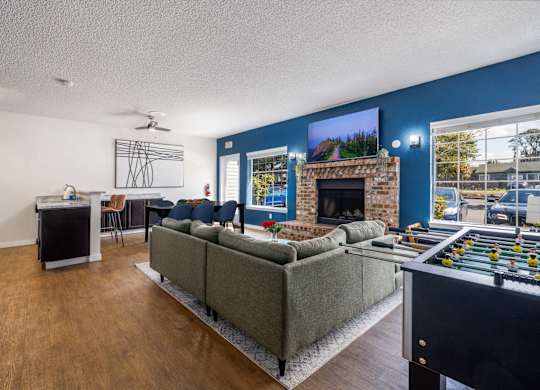 A living room with a grey couch, a fireplace, and a foosball table.