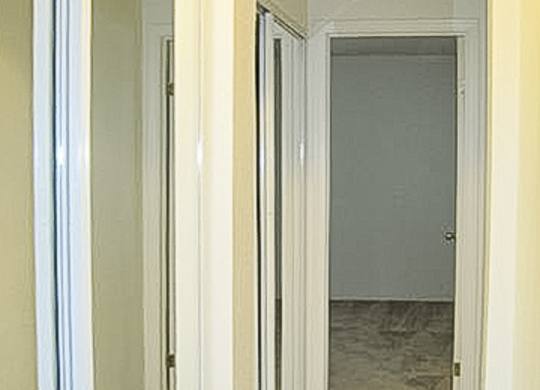 A hallway with a white door and a white wall.