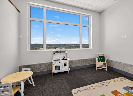 A room with a table, chairs, a small kitchenette, and a window with a view.