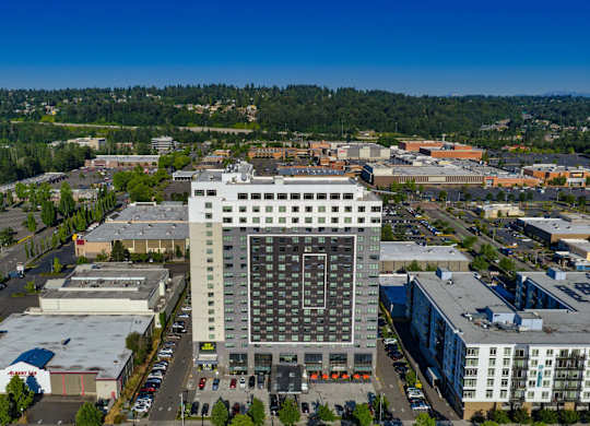 A large building with a lot of windows is in the middle of a parking lot.