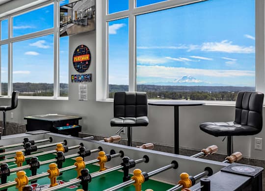 A foosball table is in a room with a view of a mountain.