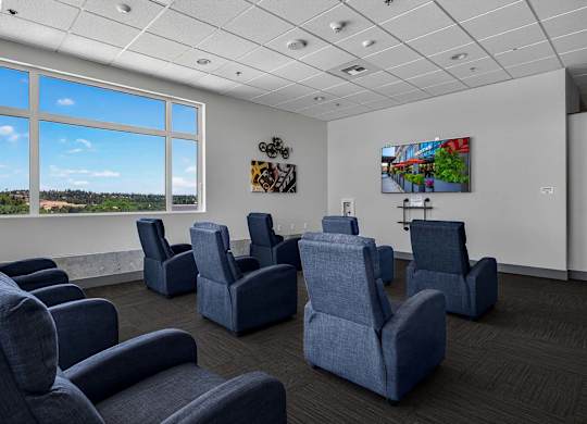 A room with blue chairs and a painting on the wall.