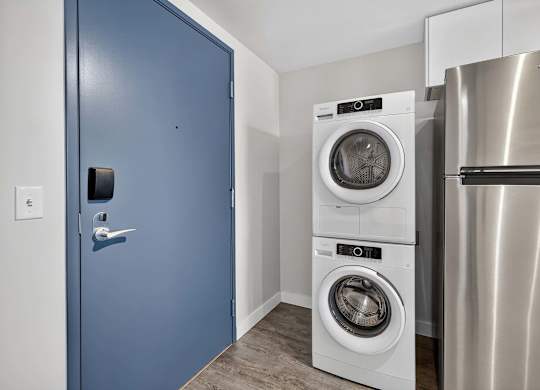 A blue door is on the left and a washing machine is in the middle of the room.