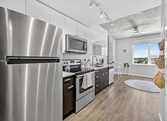 A modern kitchen with a stainless steel refrigerator and wooden flooring.