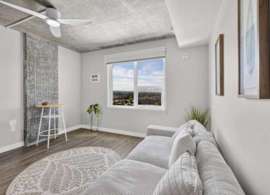 A living room with a grey couch and a ceiling fan.
