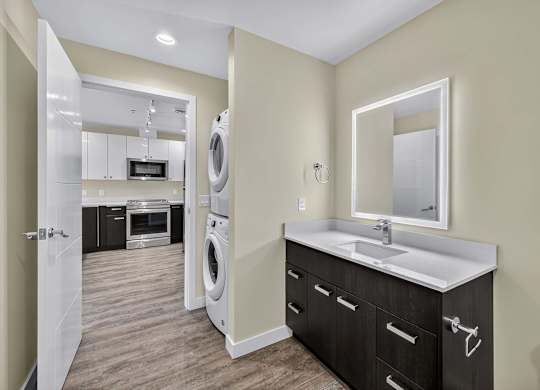 A modern laundry room with a washer and dryer built into the cabinetry.