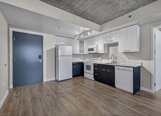 A kitchen with white cabinets and a black fridge.