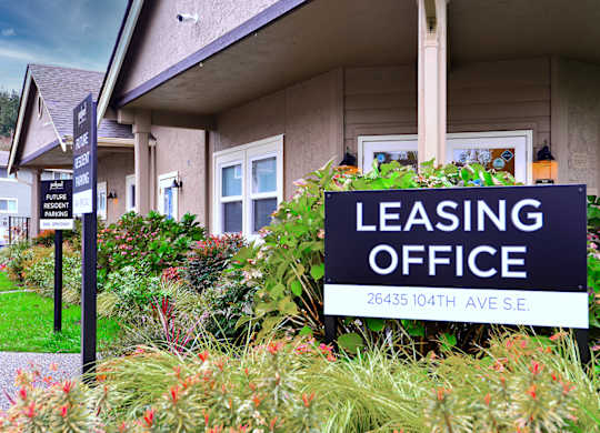 A leasing office sign is in front of a building.