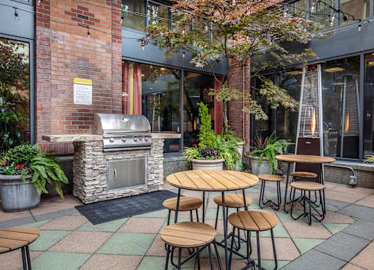 A patio with a table and chairs and a grill.