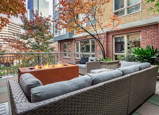 A patio with a fire pit and wicker furniture.
