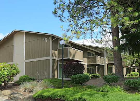 A modern building with a beige facade and a green lawn in front.