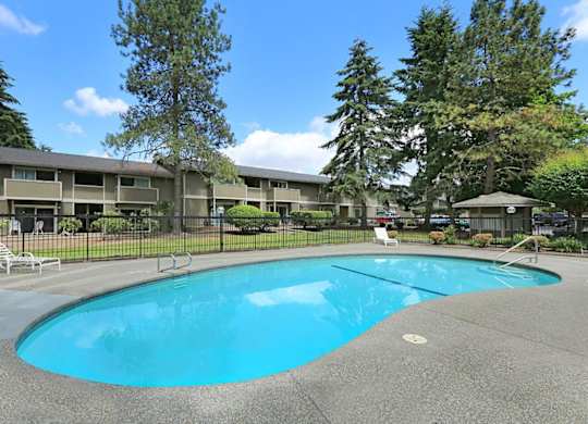 A swimming pool surrounded by trees and apartment buildings.
