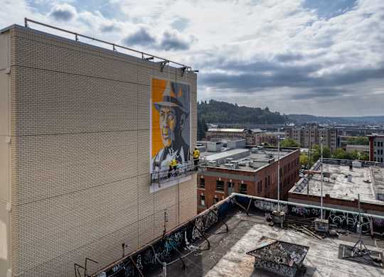 A large billboard with a man's face on it is on the side of a building.